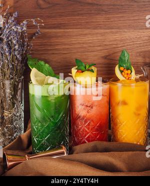 Drei bunte Cocktails mit Fruchtscheiben und Minzblättern stehen auf der Bar Stockfoto