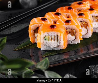 Philadelphia Sushi-Brötchen mit Lachs und Frischkäse auf schwarzem Teller serviert Stockfoto