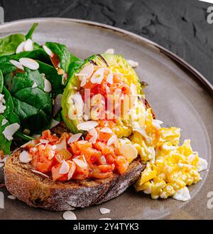 Köstliche Bruschetta mit Lachs und Avocado dekoriert mit Mandelflocken auf dunklem Hintergrund Stockfoto