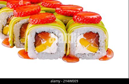 Sushi-Brötchen mit Lachs, Mango, Frischkäse mit Erdbeeren dekoriert und mit grüner Avocado und Sauce bedeckt Stockfoto