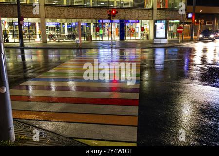 Regnerischer Asphalt, Zebraüberquerung in Regenbogenfarben führt zum Bahnhof, NachtschottLeoben, Steiermark, Österreich, Europa Stockfoto