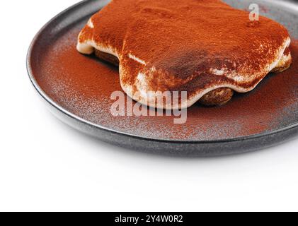 Köstliches traditionelles Tiramisu, bestreut mit Kakaopulver, präsentiert auf einer Keramikplatte Stockfoto