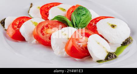 Caprese Salat ist ein klassischer italienischer Vorspeise, der aus in Scheiben geschnittenem Mozzarella, Tomaten und Basilikum besteht, mit Salz und Olivenöl gewürzt Stockfoto