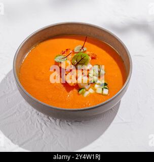 Die Schüssel ist gefüllt mit lebendiger, cremiger Tomatensuppe und garniert mit frischen Garnelen, Gurken und Gemüse Stockfoto