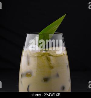 Ein Glas geeister Matcha Latte mit Tapiokaparmeln wird mit einem Palmblatt garniert und schafft ein erfrischendes und exotisches Getränk Stockfoto