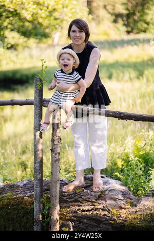 Mutter und Tochter posieren für ein Foto auf einem Zaun in der Natur Stockfoto