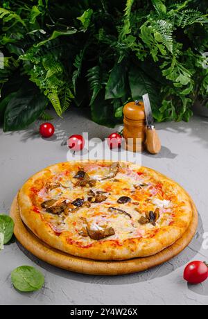 Pizza mit Schinken, Auberginen, Pilzen und Käse auf einem Holzbrett Stockfoto