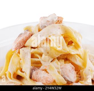 Tagliatelle-Pasta mit Lachs und cremiger Sauce wird auf einem weißen Teller serviert Stockfoto