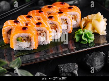 Philadelphia Sushi-Brötchen mit Lachs und Frischkäse auf schwarzem Teller serviert Stockfoto