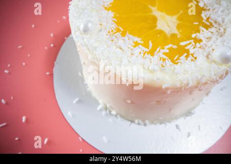 Köstlicher weißer Schokoladenkuchen, dekoriert mit Orangen- und Kokosflocken Stockfoto