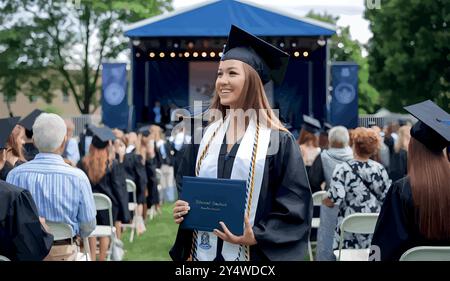 Eine stolze Hochschulabsolventin steht in ihrer Mütze und ihrem Kleid, hält ihr Diplom und lächelt, während sie nach vorne blickt. Sie markiert das Ende der harten Arbeit und einen Neuanfang. Stock Vektor
