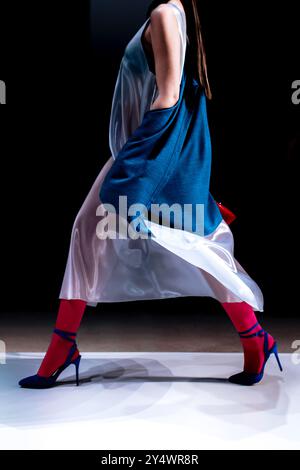 Elegantes Outfit, weißer, seidenlanger Rock, High Heels und blaue Jacke, Modemodell, das auf dem Laufsteg läuft Stockfoto