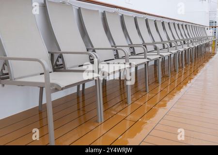 Reihe von grauen Metallliegen an der Seite des Kreuzfahrtschiffs Stockfoto