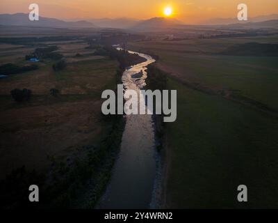 Waldfeuer Rauch Sonnenuntergang mit Blick auf ein durchströmendes Land, das durch landwirtschaftliche Felder fließt und weit entfernte Berge in Nordamerika überblickt. Stockfoto