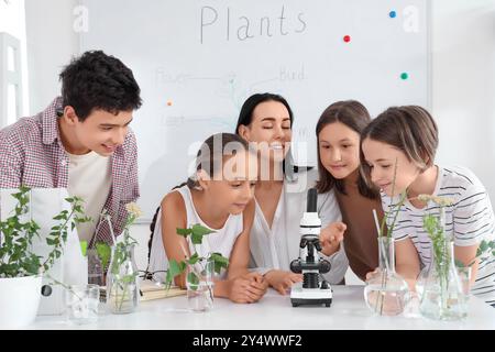 Schüler mit Lehrer und Mikroskop studieren im Biologiekurs Stockfoto