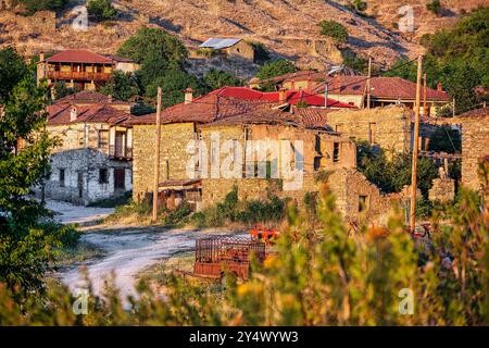 Ein Blick auf alte, verwitterte Steingebäude mit roten Ziegeldächern in Agios Germanos, Griechenland, die den rustikalen Charme des Dorfes und den traditionellen Architekten einfangen Stockfoto