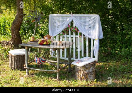 Gartenmöbel für Freizeit in der Natur. Holzmöbel im Freien für Picknick im Herbstgarten. Gemütlicher Innenhof mit Tisch und Stuhl Stockfoto