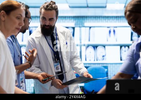 Medizinisches Team diskutiert Röntgenergebnisse und Patientenversorgungsstrategie in einem Behandlungszentrum, Expertise in Radiologie und Krankheitsprävention. Die Zusammenarbeit gewährleistet eine genaue Diagnose und Medizin. Stockfoto