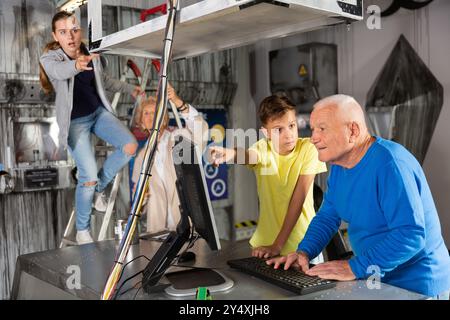 Großeltern und Enkelkinder, die sich im Fluchtzimmer mit einem Konundrommel herumtoben Stockfoto