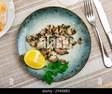 Gegrillter Tintenfisch mit Gemüse und Zitrone auf Teller Stockfoto