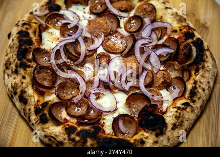 Rustikale, handgemachte Peperoni-Pizza mit roten Zwiebeln Stockfoto