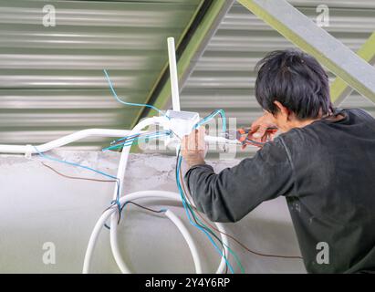 Der Techniker verzweigt Drähte mit einer Zange auf der Baustelle. Stockfoto