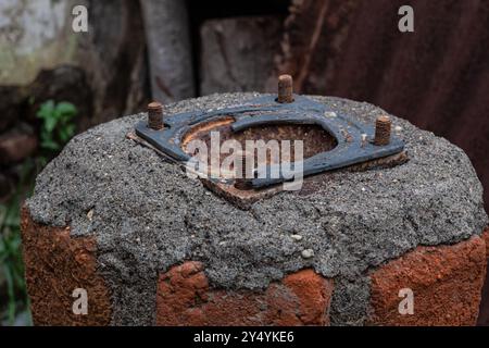 Rostige und korrodierte alte Metallmuttern, die in altem Ziegelzement stecken Stockfoto