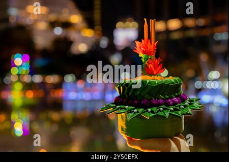 Hand hält krathong für Thailand Loy Krathong Festival mit bunten Bokeh Lichtern Hintergrund. Stockfoto