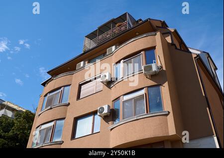 Modernes architektonisches Design eines mehrstöckigen Gebäudes mit geschwungenen Linien und weitläufigen Fenstern unter einem klaren blauen Himmel Stockfoto