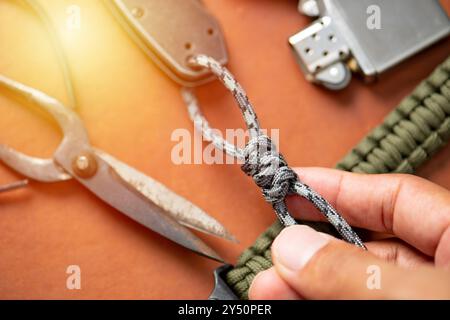 Der Mann, der Lanyard aus einem Paracord-Seil webt. Paracord oder Fallschirmseil ist ein leichtes Nylonseil. Stockfoto