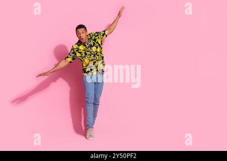 Ganzkörperfoto des attraktiven jungen Mannes verängstigt halten Balance gekleidete stilvolle tropische Druck Kleidung isoliert auf rosa Hintergrund Stockfoto