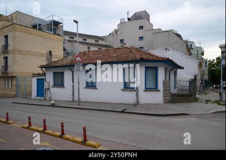 Charmantes einstöckiges Haus mit blauen Akzenten in einer ruhigen Straße in einem belebten Stadtgebiet bei bewölktem Wetter Stockfoto