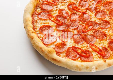 Nahaufnahme einer Peperoni-Pizza mit roten Chilischeiben auf weißem Hintergrund. Stockfoto