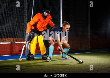 Eine Eishockeyspielerin greift den Torwart an, um ein Tor zu erzielen. Stockfoto