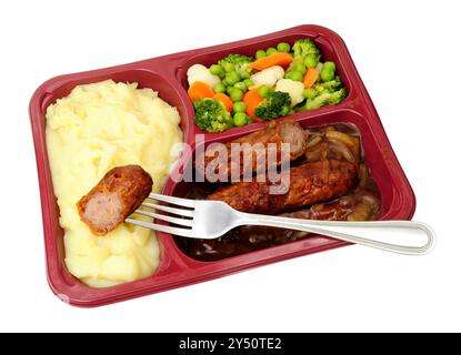 Fertiggerichte mit Wurst und Püree mit Schweinefleisch, Kartoffelpüree, Zwiebelsoße und gemischtem Gemüse in einer Plastikschale Stockfoto