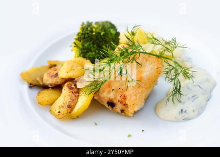 Gebratenes Fischfilet mit Bratkartoffeln, Brokkoli, Remoulade-Sauce und Dill-Beilage, serviert auf einem weißen Teller, gesunder Gang in einem Abendmenü, Copy Spac Stockfoto