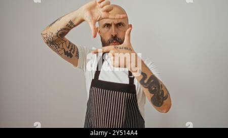 Hispanischer Mann mit Bart und Tätowierungen in der Schürze, der eine Geste auf weißem Hintergrund macht Stockfoto