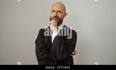 Hispanischer Mann, der ein schwarzes Gewand trägt, posiert mit der Hand auf dem Kinn, isoliert über einem weißen Hintergrund, in einem nachdenklichen Ausdruck, der Erwachsene männliche zeigt Stockfoto