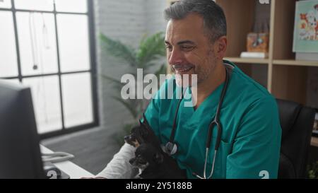 hispanischer Tierarzt mittleren Alters, der in einer Tierklinik mit zwei Chihuahuas im Innenbereich arbeitet. Stockfoto