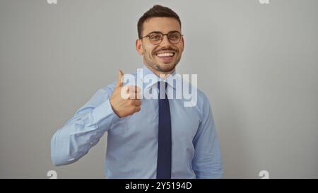 Hübscher junger hispanischer Mann mit Bart und Brille, der die Daumen hochlegt, während er selbstbewusst lächelt, isoliert über einem weißen Hintergrund. Stockfoto