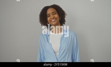 Eine schöne junge afroamerikanische Frau mit lockigem Haar lächelt warm über einem isolierten weißen Hintergrund. Stockfoto