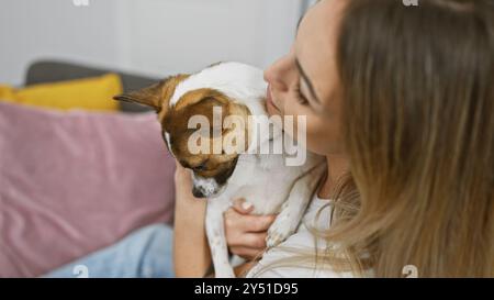 Die blonde Frau hält liebevoll einen kleinen Hund drinnen und zeigt eine liebevolle Beziehung zwischen Haustierbesitzern. Stockfoto