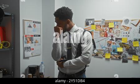 Nachdenklicher afroamerikanischer Mann, ein Detective, der in einer Polizeiwache nachdenkt, umgeben von Ermittlungsbeweisen. Stockfoto