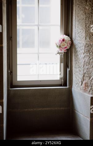 Hochzeitsstrauß aus rosa und weißen Rosen an einem Fenster in sanftem Licht. Stockfoto