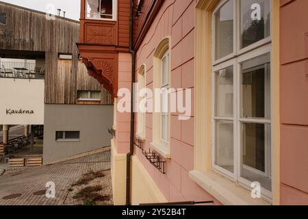 Rosafarbene und gelbe Fassade spiegelt sich in den Fenstern des modernen Cafés wider Stockfoto
