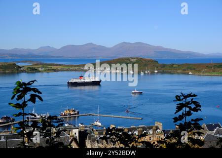 Oban, Schottland, Großbritannien. September 2024. Herrliches warmes und sonniges Wetter in Oban und an der Westküste mit Blick auf die Stadt und den Hafen und Blick auf die Berge von Mull. Die sonnigen Bedingungen werden voraussichtlich über das Wochenende andauern. Caledonian MacBrayne Fähre „Isle of Mull“, Abfahrt nach Craignure auf der Isle of Mull. Blick vom McCaig's Tower. Quelle: Craig Brown/Alamy Live News Stockfoto