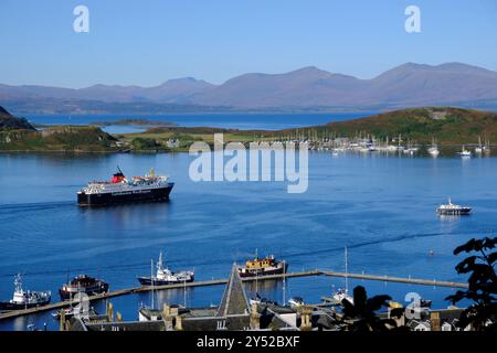 Oban, Schottland, Großbritannien. September 2024. Herrliches warmes und sonniges Wetter in Oban und an der Westküste mit Blick auf die Stadt und den Hafen und Blick auf die Berge von Mull. Die sonnigen Bedingungen werden voraussichtlich über das Wochenende andauern. Caledonian MacBrayne Fähre „Isle of Mull“, Abfahrt nach Craignure auf der Isle of Mull. Blick vom McCaig's Tower. Quelle: Craig Brown/Alamy Live News Stockfoto