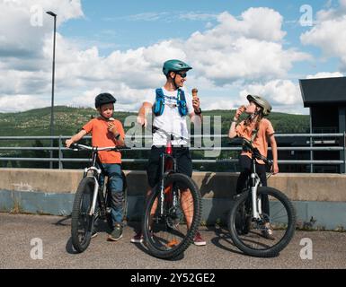Vater und zwei Kinder essen Eis während einer Fahrradtour in Norwegen Stockfoto