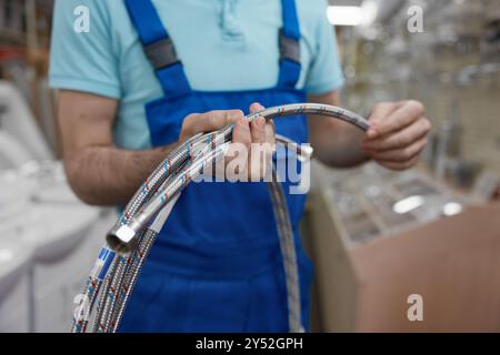 Abgeschnittener Schuss eines Mannes Klempner, der im Einkaufszentrum Leitungen hält Stockfoto