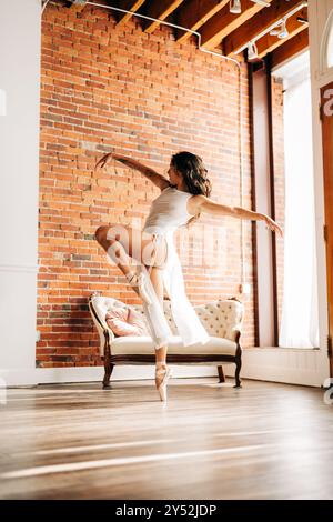 Balletttänzerin in Mittelstellung mit ausgestreckten Armen in einem Loft-Studio Stockfoto